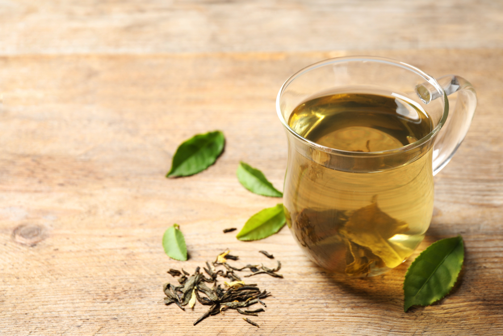 Cup of green tea, dry and fresh leaves