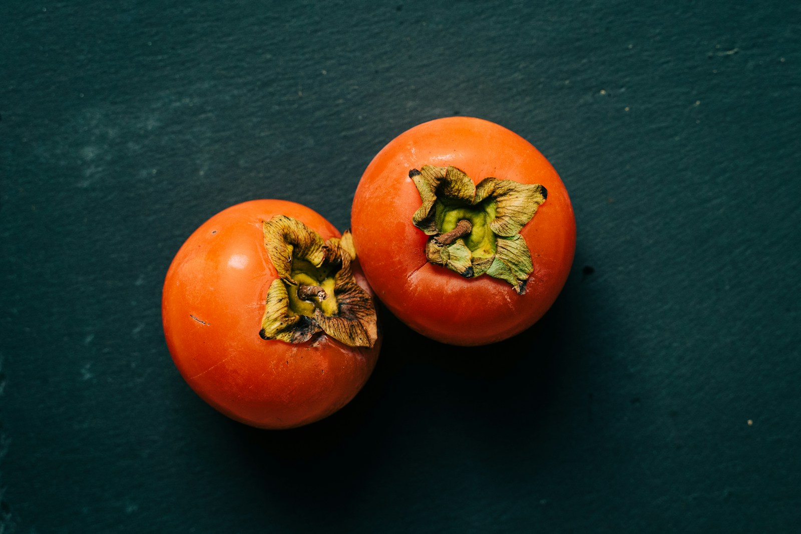 3 red persimmon on black textile